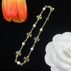TORY BURCH's new pearl necklace, a stylish accessory for couples.